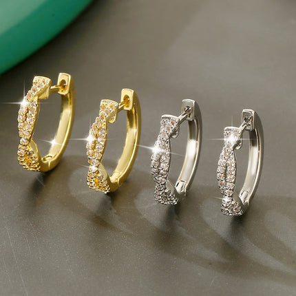 Elegant braided hoop earrings with sparkling crystal details in gold and silver finish.